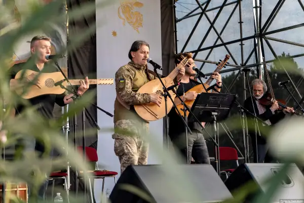 Музиканти, серед них військовослужбовець, співають і грають на бандурах та скрипці.